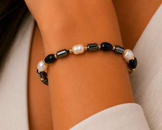 Woman wearing black and faux pearl beaded stretch bracelet with gold-tone spacers