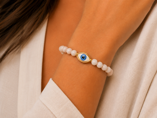 Blush and white agate-tone beaded bracelet with gold-rimmed evil eye charm