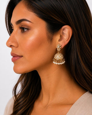 Woman wearing gold-tone crystal star pavé jhumka earrings with faux pearl fringe
