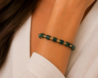 Woman wearing green faceted bead stretch bracelet with gold-tone spacers