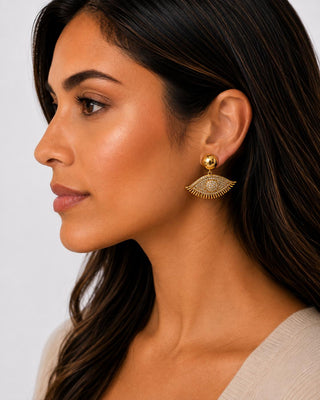 Woman wearing gold-tone winking eye earrings with pavé faux crystals
