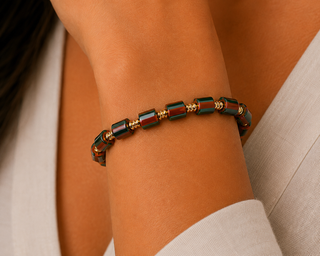 Woman wearing green and burgundy striped bead stretch bracelet with gold-tone spacers