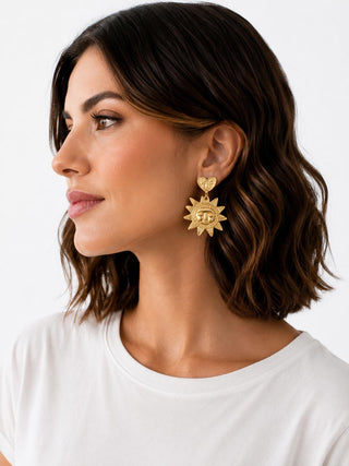 Model wearing Golden Sun Heart Earrings — gold heart stud with sun medallion drop