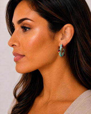 Woman wearing turquoise enamel gold-tone hoop earrings with faux garnet stones